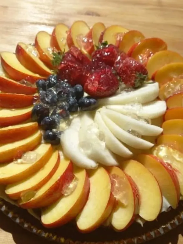 Tarta húmeda cubierta con gajos de manzana y frutas patagonicas